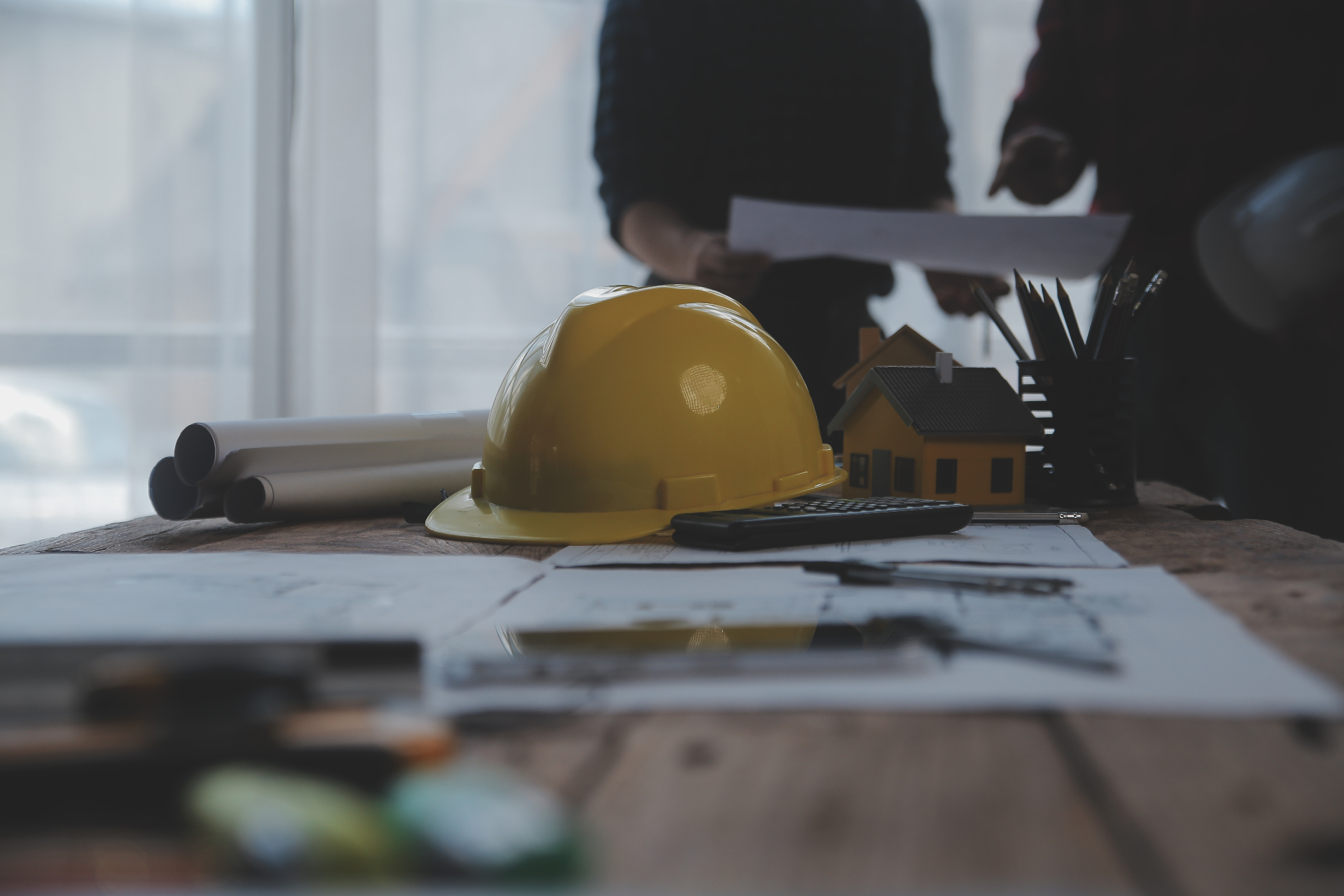 General contractors reviewing blueprints with a hard hat and model home