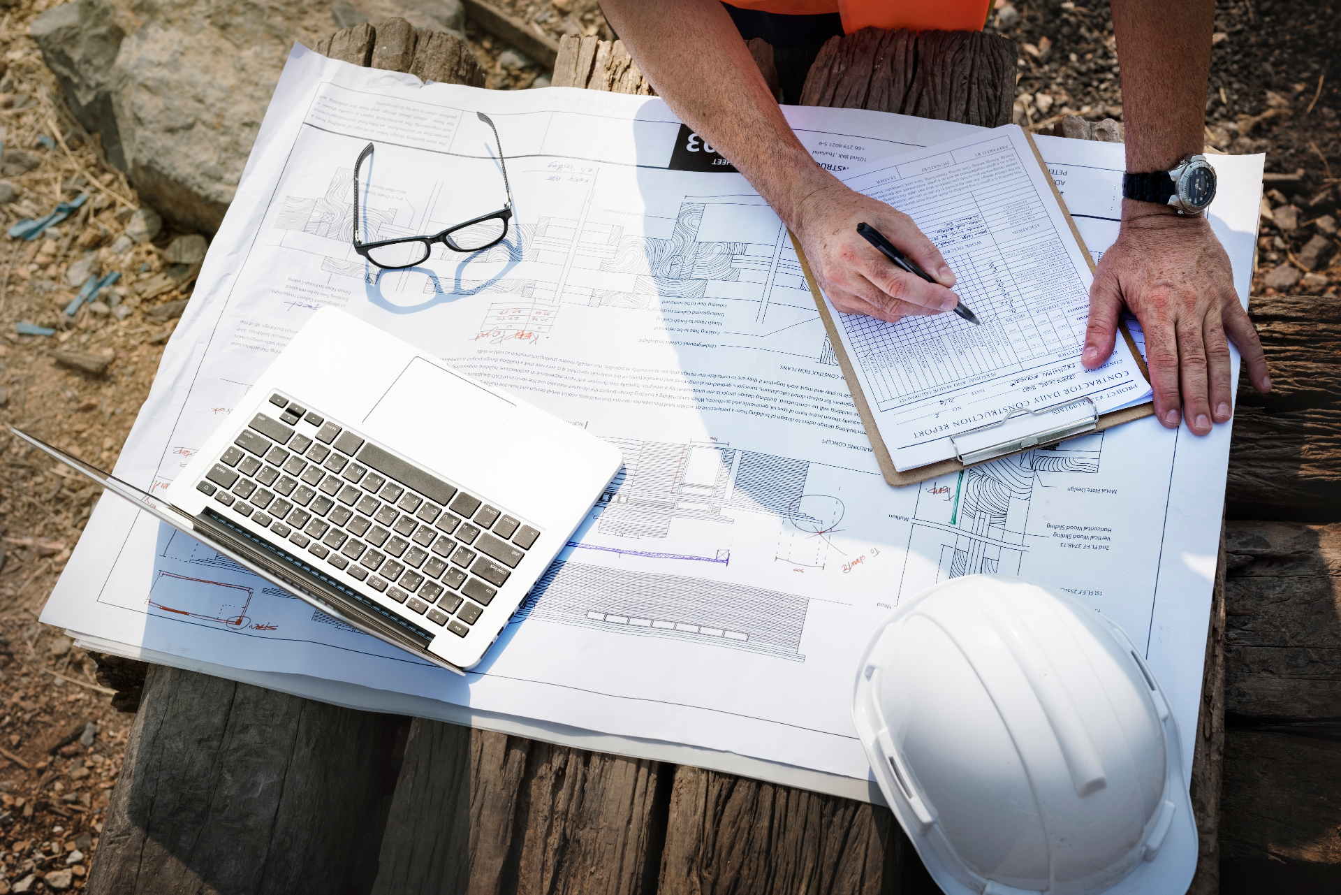 Contractor filling out permit paperwork over construction plans